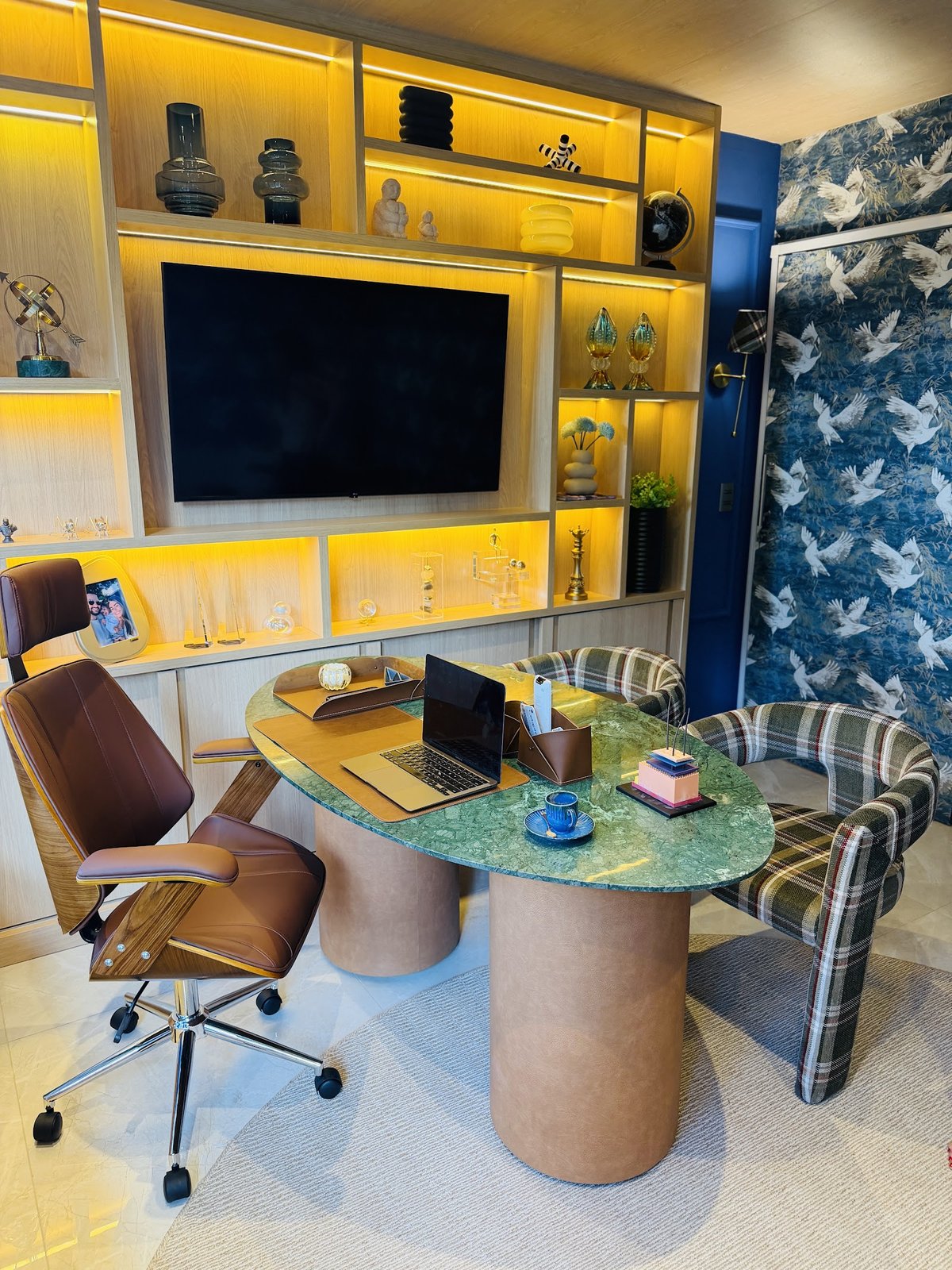 Consultório do Núcleo Capellare com mesa, poltronas e estante iluminada